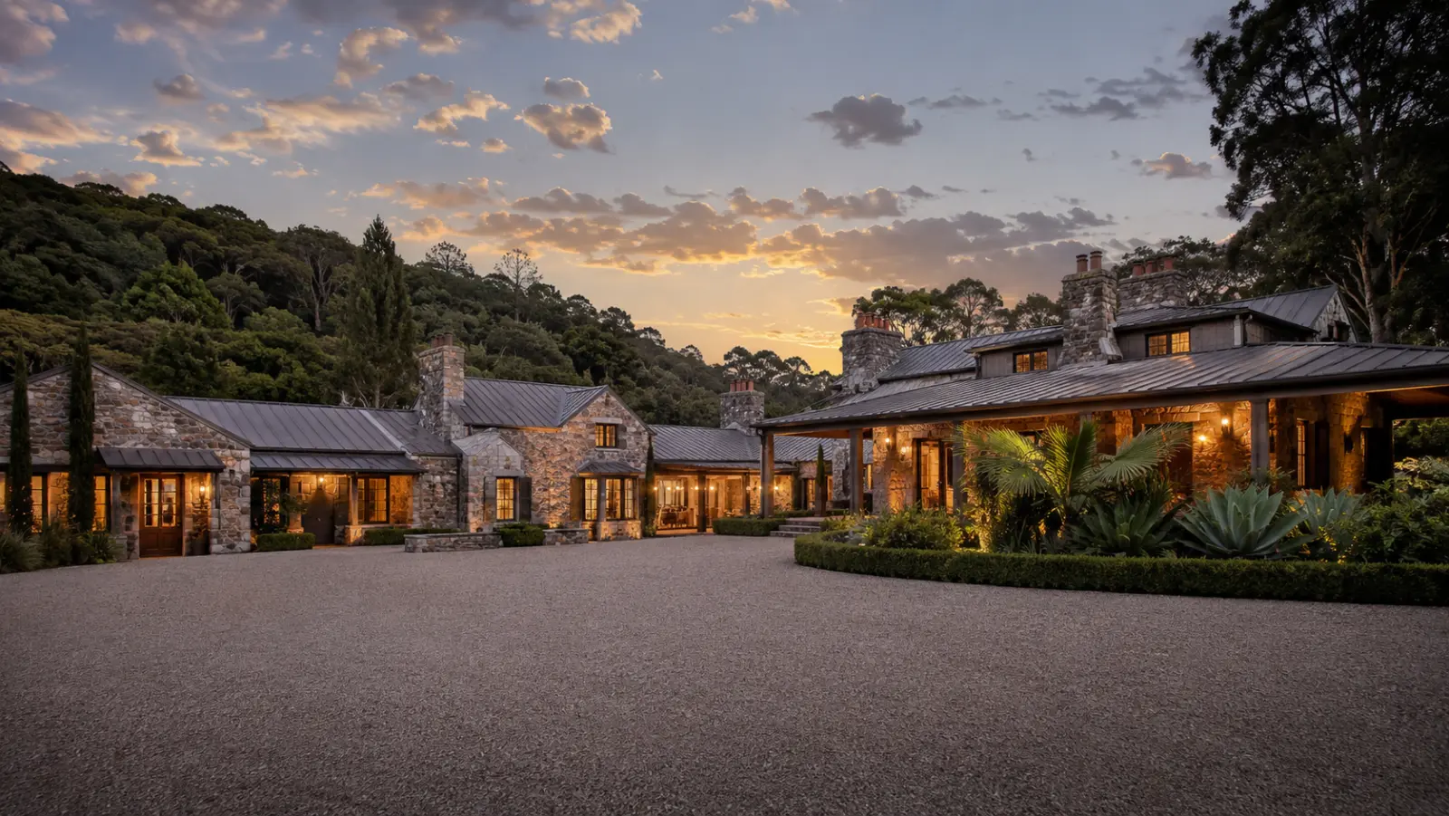 The stone main house at Roy Hinterland lit from within at dusk